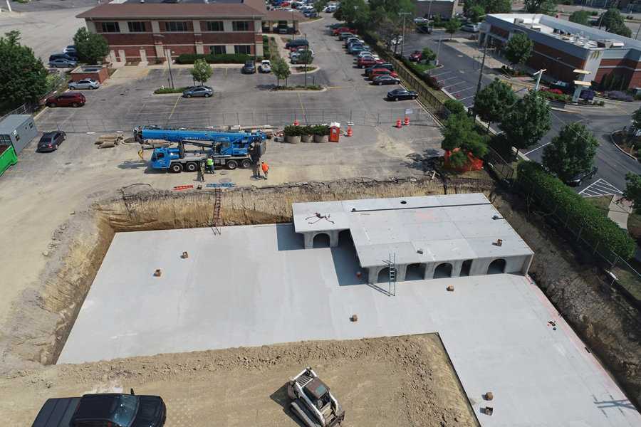 DJI_0789 Excavated site with newly poured concrete foundation, construction equipment, and workers overseeing the area.