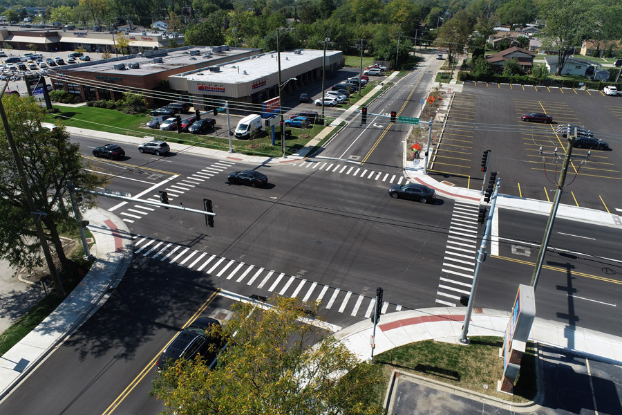 Lee-Forest-DJI_0117 Aerial view of a newly designed intersection featuring marked crosswalks, traffic signals, and adjacent commercial buildings.