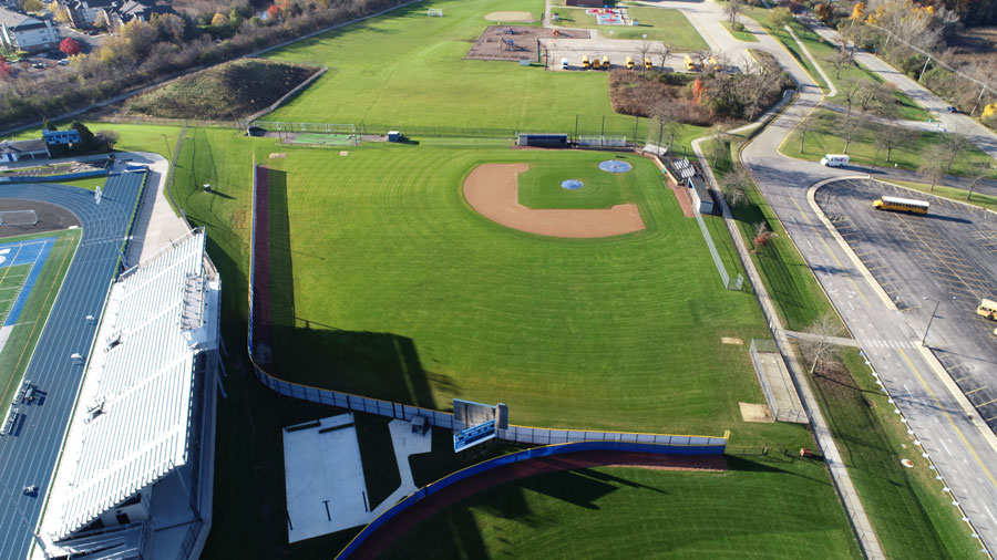 DJI_0008-Web Aerial view of a well-maintained baseball field adjacent to a sports complex, with green grass and surrounding municipal areas.