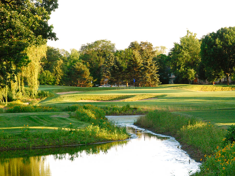 Wilmette-GC-3-web Serene golf course landscape featuring manicured greens, trees, and a gently flowing stream, enhancing the natural beauty of the area.
