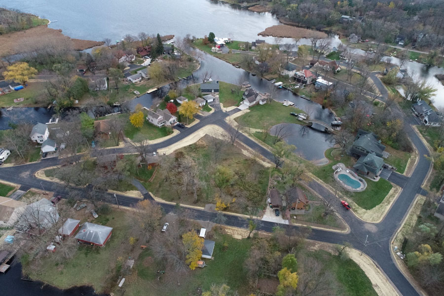 Knollwood-DJI_0282_web Aerial view of a residential neighborhood featuring newly constructed roads, homes, and a lake, surrounded by autumn foliage.