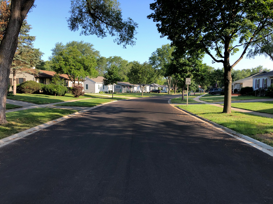 IMG_4069-edit_web Freshly paved residential street lined with trees and well-maintained homes, showcasing municipal infrastructure improvements.