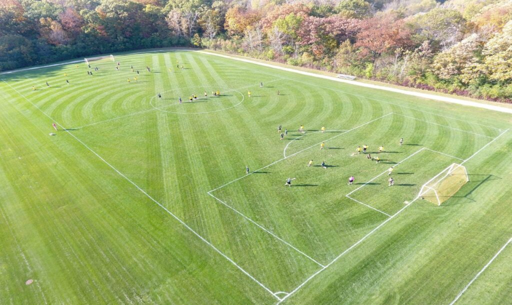 A recently mowed soccer field in use. Showing the importance of Athletic field maintenance, the field has a nice mow pattern, and is very green.