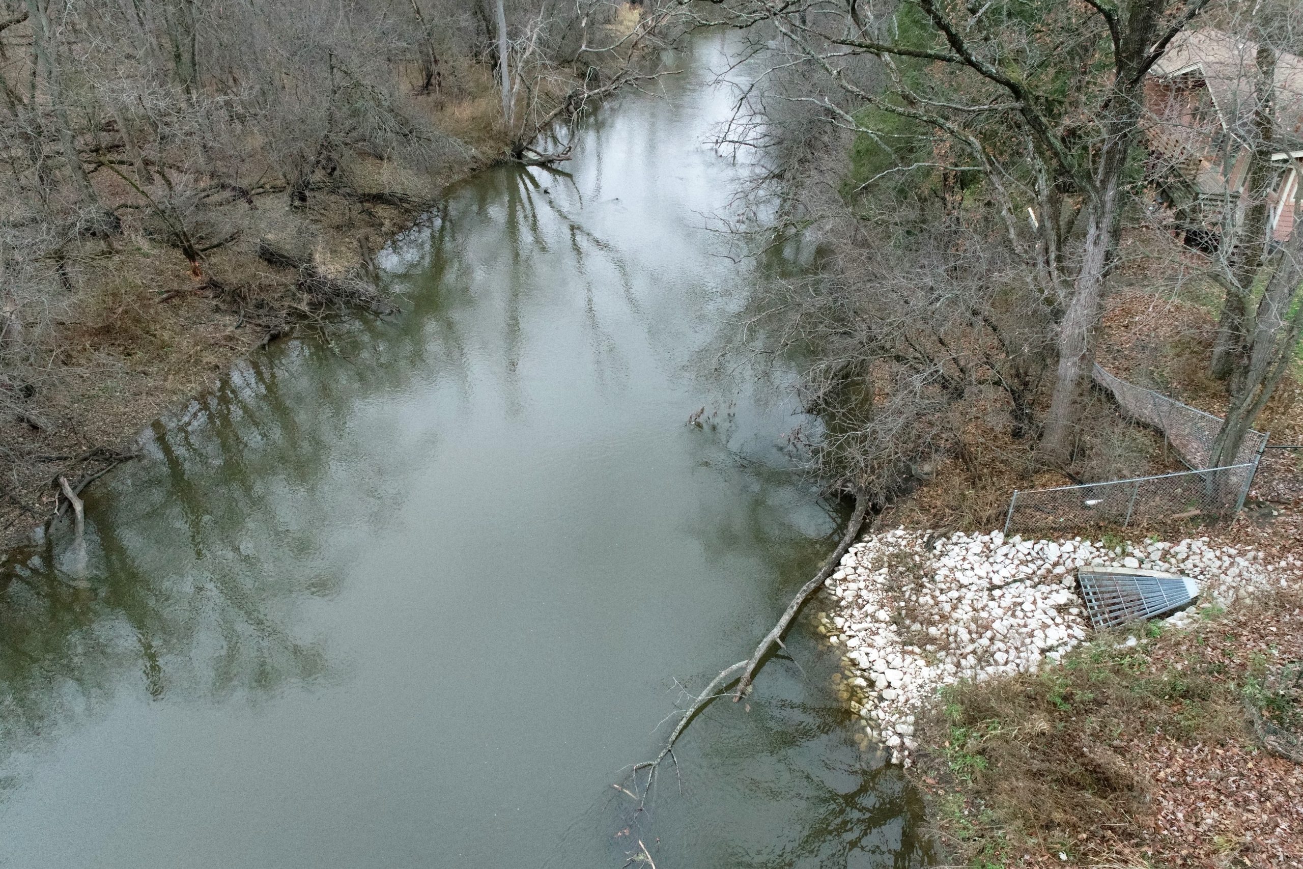 DCIM100MEDIADJI_0636.JPG A peaceful creek lined with trees and a protective stone barrier along its banks, showcasing areas for potential municipal improvement.