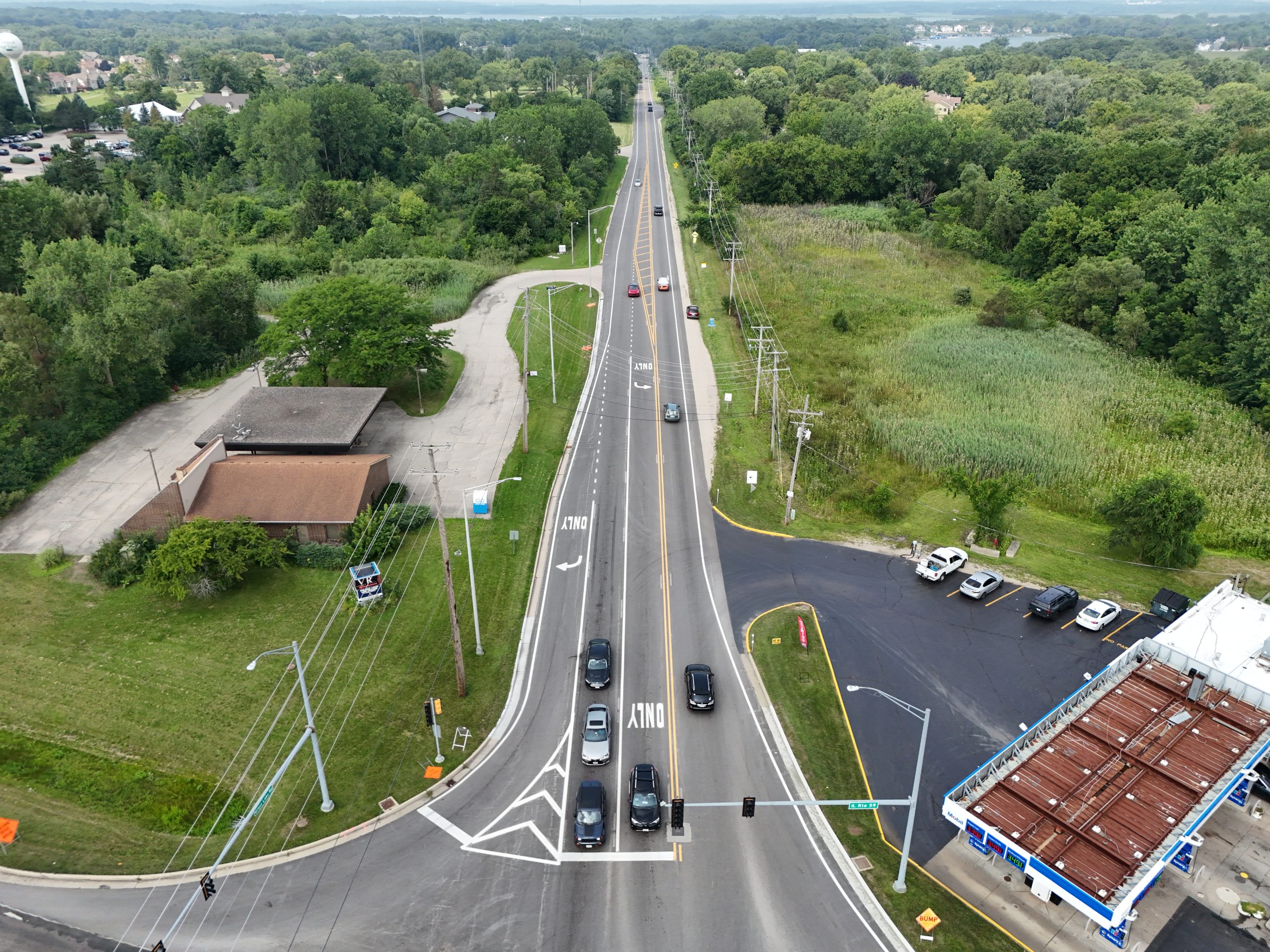 default Aerial view of a busy roadway with traffic, surrounded by green spaces and commercial developments, showcasing infrastructure elements.
