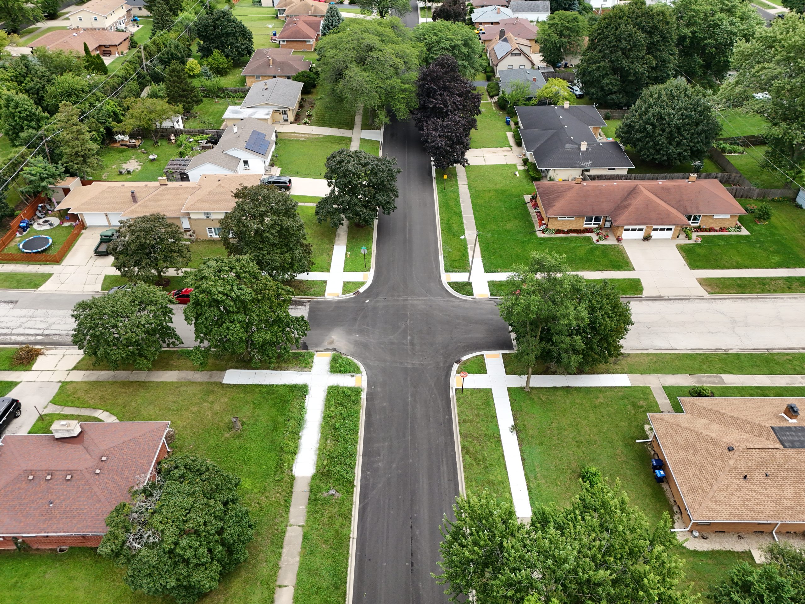 default Aerial view of a residential neighborhood showcasing newly paved roads, landscaped yards, and tree-lined streets.